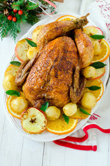 Christmas baked chicken (turkey) with oranges and apples on a wh