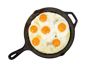Fried eggs on cast iron skillet with salt and pepper isolated on white background