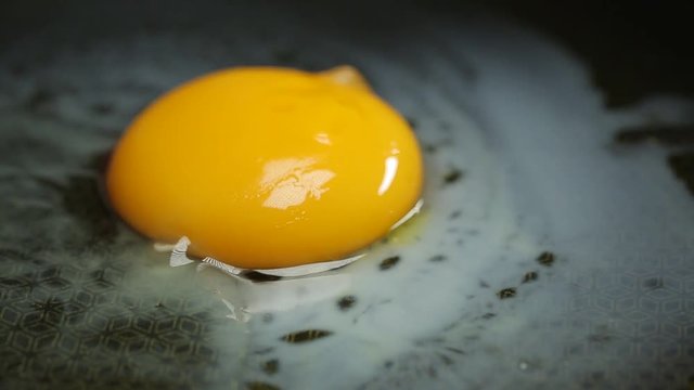 Fried eggs on ceramic frying pan with oil FullHD footage