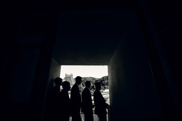Silhouettes of five men standing in dark corridor