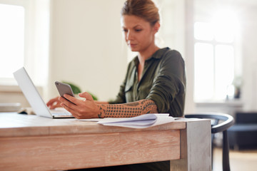 Woman at home office using mobile phone