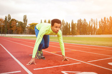 Young sporty man are ready to run on racetrack. Fit well formed people at large nice modern stadium