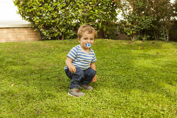 Full shot portrait cute smiley baby boy with pacifier squat in t