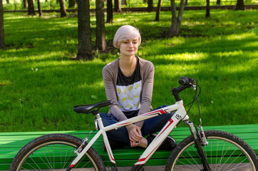 Naklejka premium Young girl with bicycle in the park