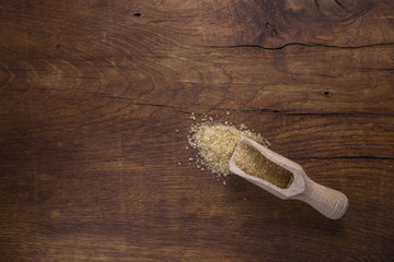  Spoon with brown sugar, on old wooden background.