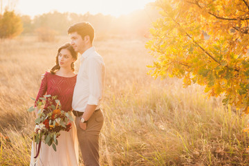 Stylish and romantic caucasian couple in the beautiful autumn park. Love, relationships, romance, happiness concept. Bouquet in girl's hands.