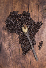 Roasted coffee beans arranged in the shape of Africa on old wood