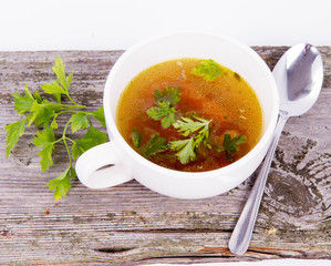 Chicken soup with carrots and parsley on wooden background