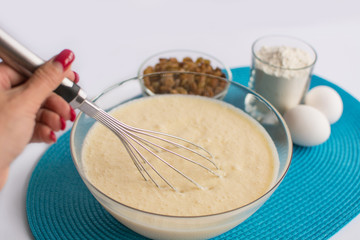 glass bowl with dough and whisk in a female hand, set of product