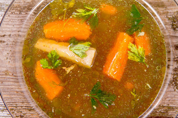 Chicken soup with carrots and parsley on wooden background