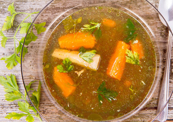 Chicken soup with carrots and parsley on wooden background