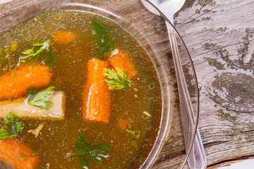 Chicken soup with carrots and parsley on wooden background