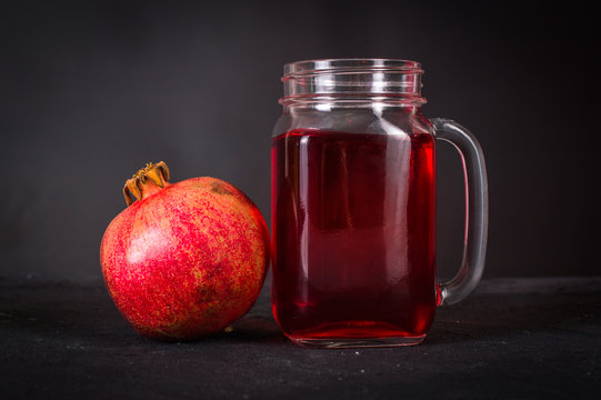 pomegranate juice in the jar with a handle on a dark background
