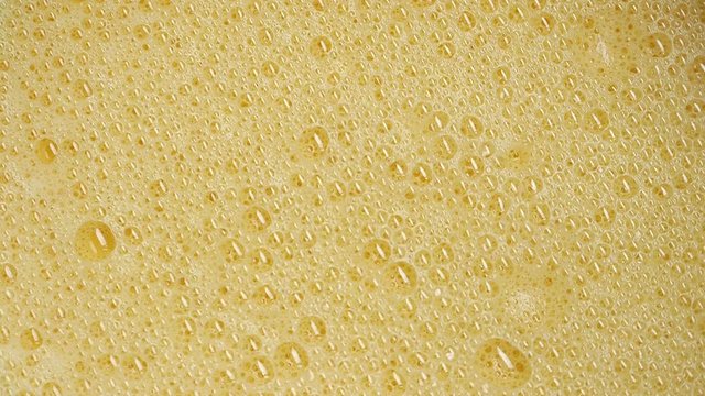 Bursting yellow bubbles of whisking eggs for fried omelette