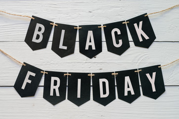 Fototapeta premium Black Friday paper banner garland lettering hanging on white barn wood planks background. Beautiful holiday flyer.