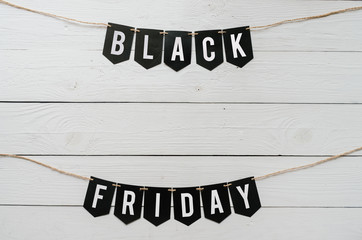Black Friday paper banner garland lettering hanging on white barn wood planks background. Beautiful holiday flyer template. Empty space for text, copy.
