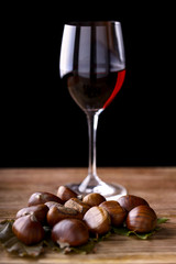 chestnuts and glass of red wine on wooden table