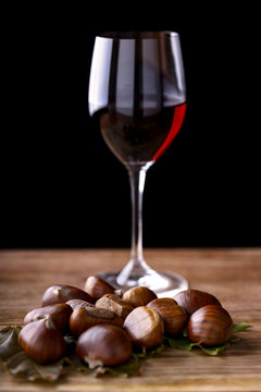 chestnuts and glass of red wine on wooden table