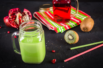 Smoothies of kiwi juice pomegranate juice in the jar with a handle on a dark background