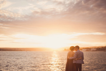 Romantic and stylish caucasian couple hugging at sunrise. Love, relationships, romance, happiness concept.