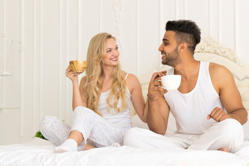 Obraz na płótnie Canvas Young Couple Drink Coffee Sitting In Bed, Happy Smile Young Hispanic Man And Woman Lovers Hold Cups Bedroom
