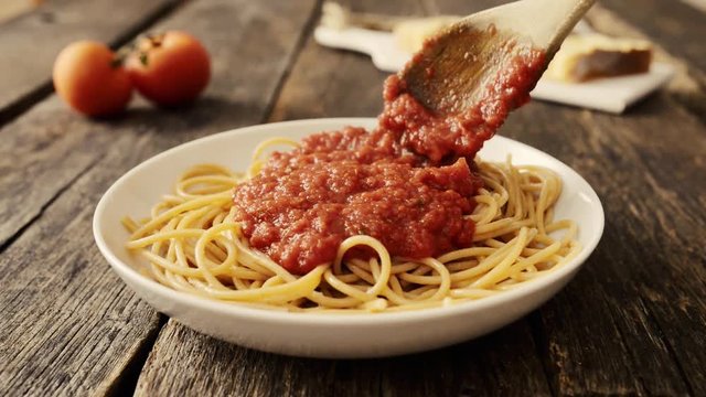 Pouring tomato sauce on pasta