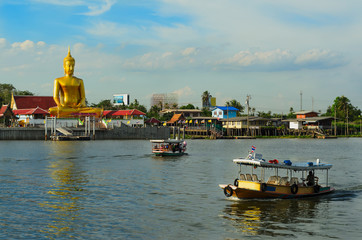 River boats crossing the Chao Phraya river in Bangkok, Thailand,with a giant golden buddha and thai houses in the background