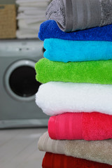 olorful stack of folded towels with washing machine in background