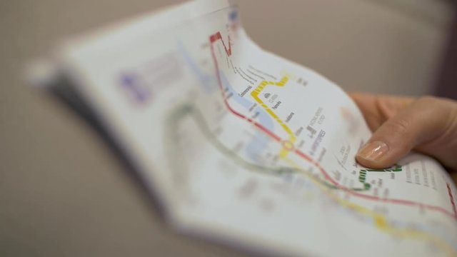 Slow motion close-up shot of a woman exploring underground map in moving subway train with following view of line scheme in the carriage
