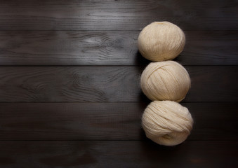 Skeins of white yarn are on a brown wooden table.