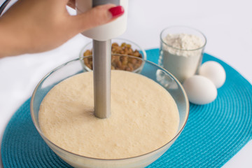 glass bowl with dough and whisk in a female hand, set of product