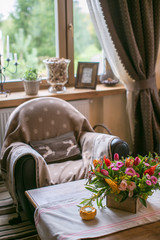 Daybed with cushions in rustic home. on the table bouquet of flowers and a candlestick pumpkin