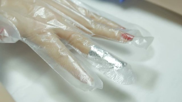 Manicurist removing the old gel polish using foil