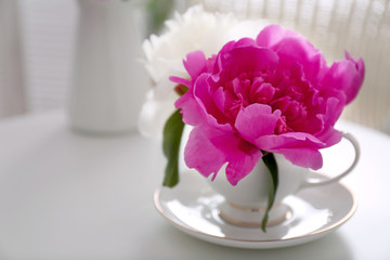 Flower bouquet of peonies in cup on table