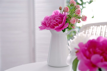 Flower bouquet of peonies in jug on table