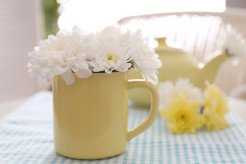 Flower bouquet of white chrysanthemum in cup on blue napkin