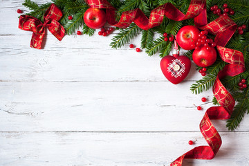 Christmas wooden background with branches of trees, apples, berries and red ribbon