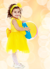 Little girl in yellow dress with big ball