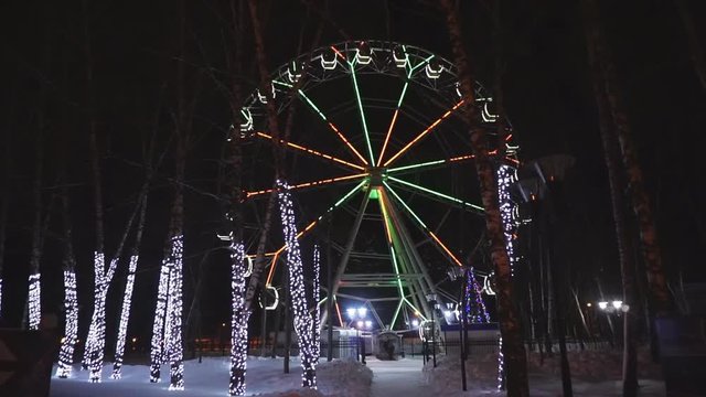 Ferris wheel rotating at amusement park under dark night sky