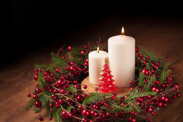Christmas wreath two white burning candle on wooden table dark background