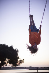 Adult woman swinging upside down on a swing at a park in San Diego, California. 