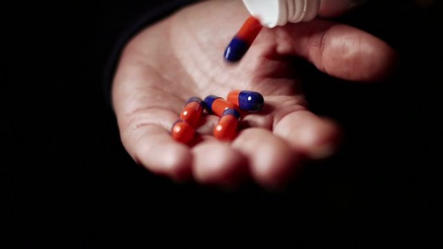 Adult woman spill on hand pills. Addiction concept. Female pours bunch of pills into the palm of her hand in a dark room slow motion