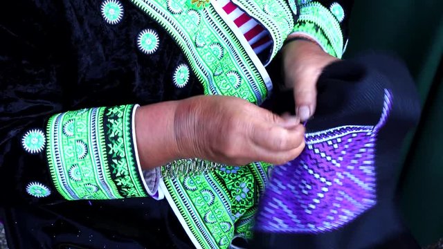 Close-up female hand of Hmong hilltribe embroider pattern colored thread.