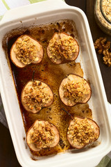 Sweet baked pear halves topped with a crisp crust of oatmeal, sugar and walnut, sprinkled with cinnamon, photographed overhead with natural light (Selective Focus, Focus on the top of the crusts)
