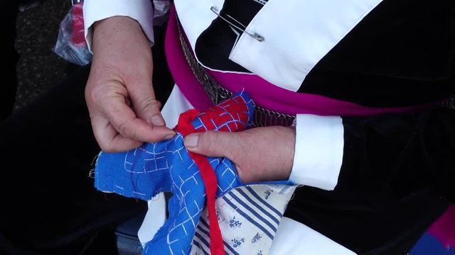 Close-up female hand of Hmong hilltribe embroider pattern colored thread.
