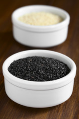 Black and white sesame seeds in small bowls, photographed with natural light (Selective Focus, Focus in the middle of the black seeds)