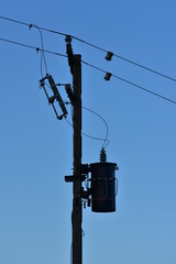 Obraz premium Silhouette of pole with electric wires and isolators.