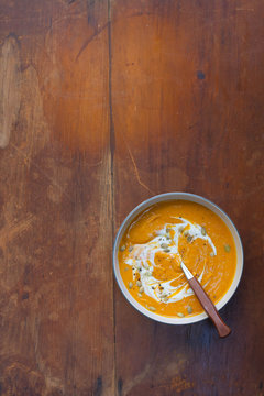 Butternut squash/ pumpkin soup with yogurt and pumpkin seeds. Rustic weathered wood tabletop. 