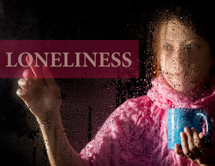 loneliness written on virtual screen. young woman melancholy and sad at the window in the rain, she holding a cup of hot coffee or tea