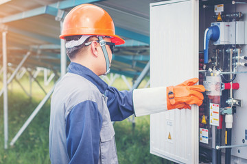 an engineer working on checking equipment in solar power plant; checking array box or inverter